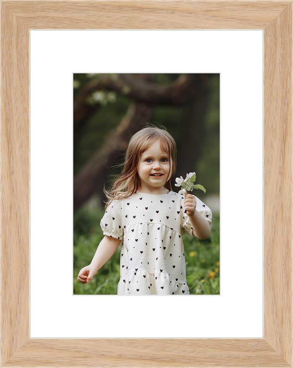 "Framed photo of a young girl holding a flower in an outdoor setting. "