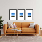Living room with orange sofa and three framed Eiffel Tower photos on the wall.